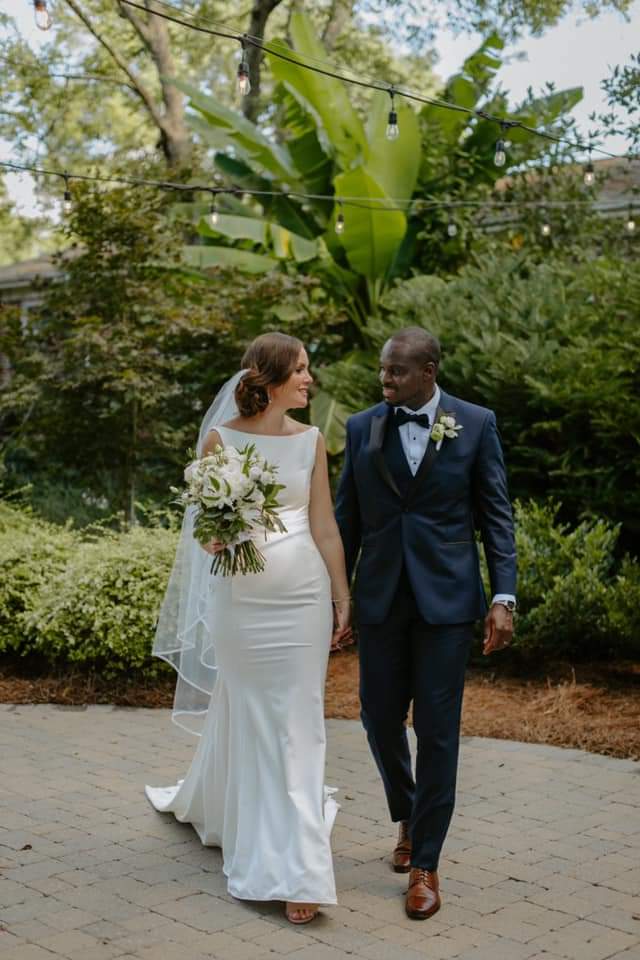 Mariés se tenant la main en marchant dans un jardin après la cérémonie