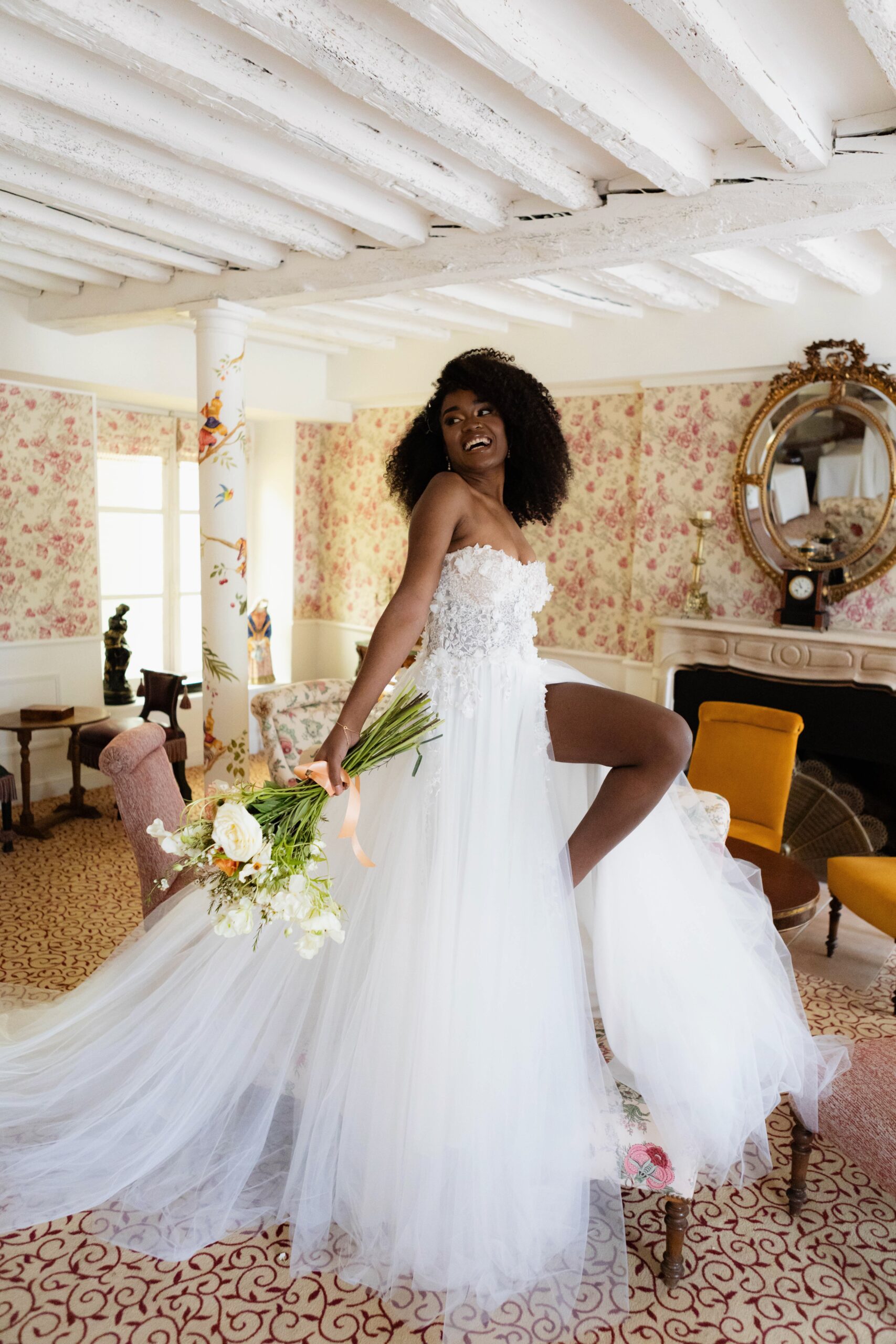 Mariée joyeuse en robe de tulle, tenant un bouquet dans un salon fleuri