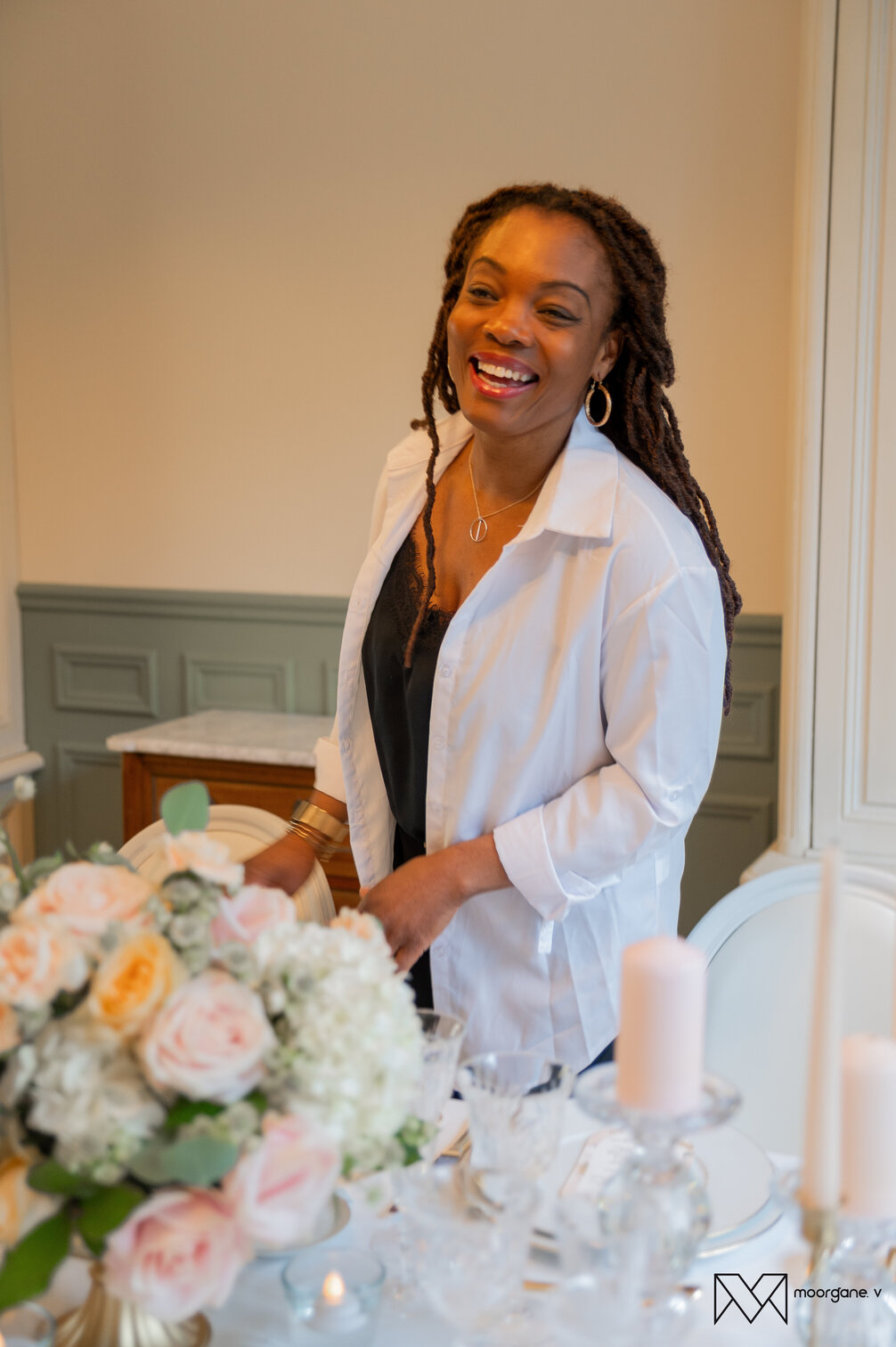 Roselaine, wedding planner, souriante en décorant une table de mariage florale