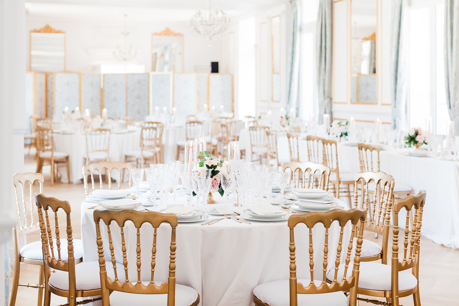 Salle de réception lumineuse avec tables rondes dressées pour un mariage élégant
