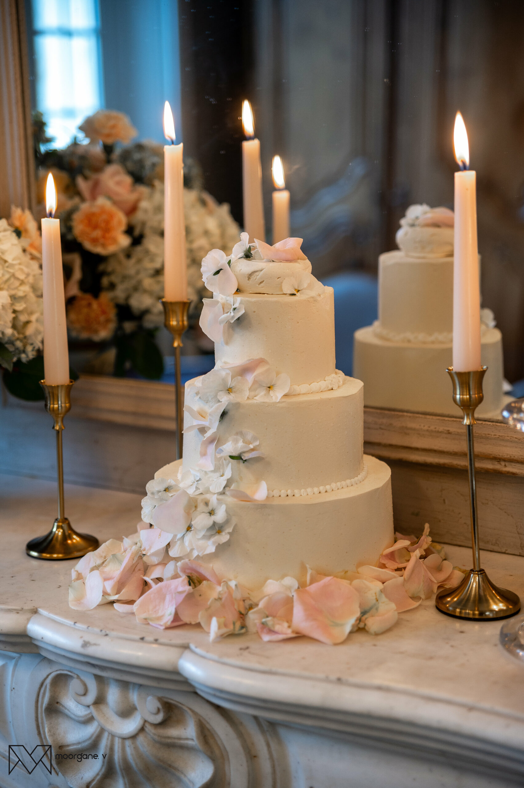Wedding cake blanc à trois étages avec fleurs pastel et bougies dorées