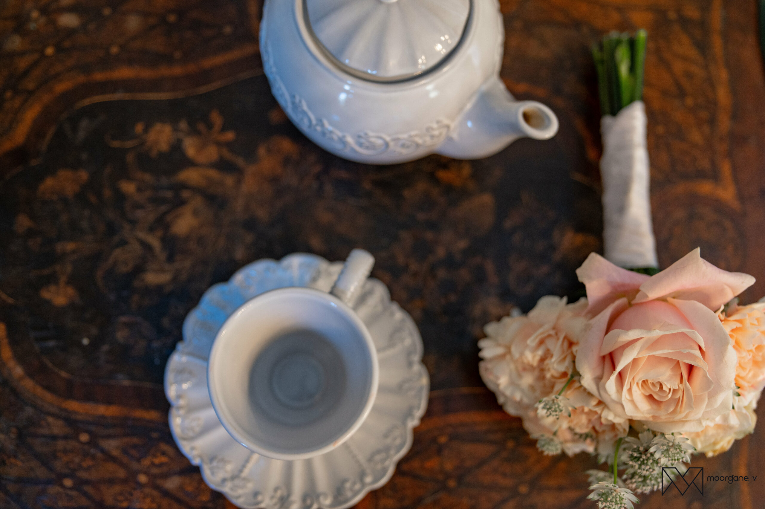 Petit bouquet de mariée posé à côté d’une tasse et théière en porcelaine blanche