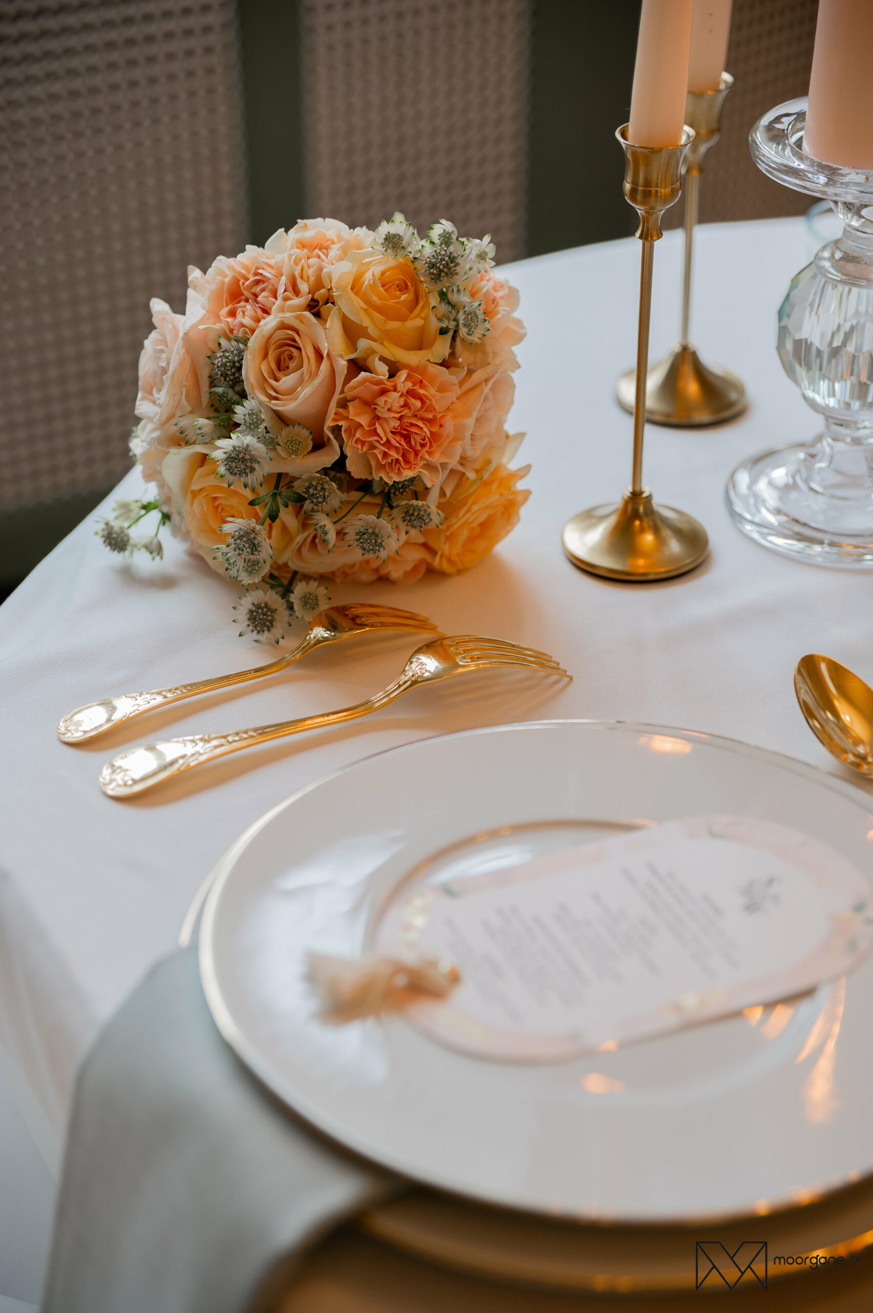Menu de mariage posé sur une assiette blanche avec bouquet pastel et couverts dorés