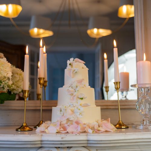 Wedding cake élégant à trois étages orné de fleurs pastel et bougies dorées