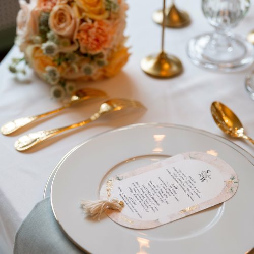 Menu de mariage élégant posé sur une assiette en porcelaine dorée