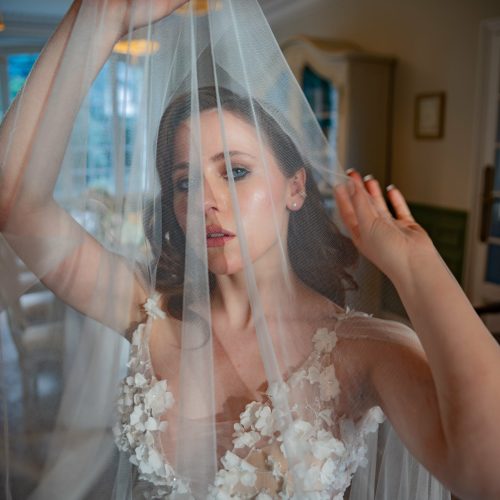 Mariée élégante tenant son voile, regard intense avant la cérémonie