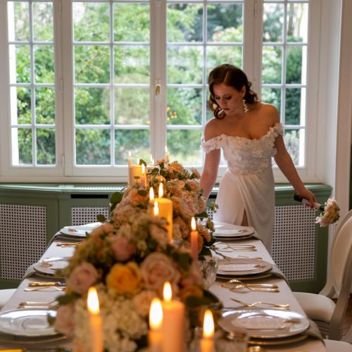 Mariée élégante observant une table de mariage ornée de bougies et fleurs pastel